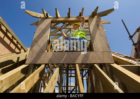 Un constructeur travaillant sur le toit d'une maison neuve. Banque D'Images