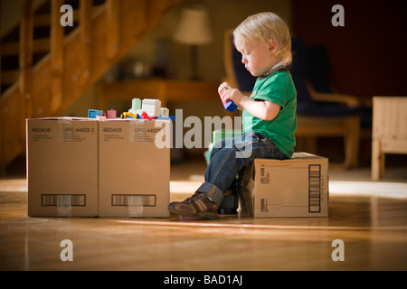 Enfant jouant avec des jouets sur des boîtes de carton Banque D'Images