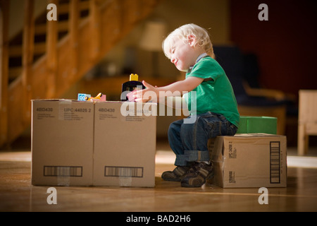 Enfant jouant avec des jouets sur des boîtes de carton Banque D'Images