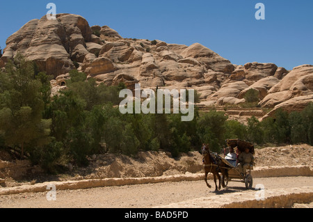 Un cheval et le chariot transportant les touristes galops dans l'ancienne ville nabatéenne de Pétra en Jordanie Banque D'Images