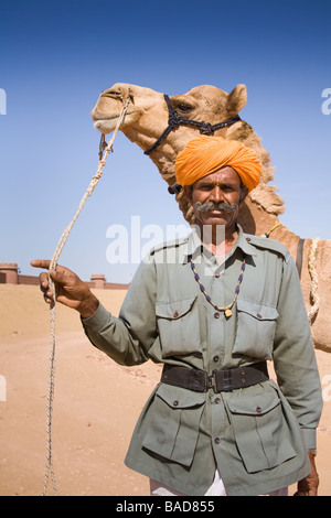 Homme debout à côté d'un chameau à Osian Camel Camp, Osian, Rajasthan, Inde Banque D'Images