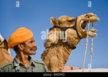 Homme debout à côté d'un chameau à Osian Camel Camp, Osian, Rajasthan, Inde Banque D'Images