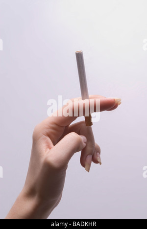 Woman's hand holding une cigarette sur un fond blanc. Banque D'Images