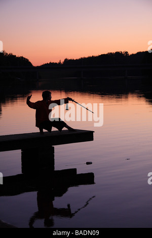 Une jeune femme en silhouette sur une jetée au coucher du soleil la pratique du tai chi avec une épée Limousin France Banque D'Images