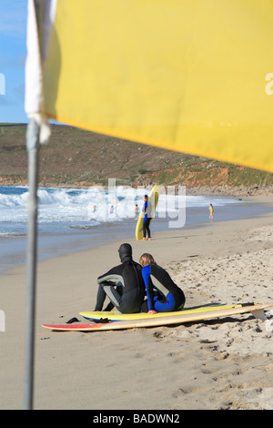 Sennen Cove beach jeunes surfeurs surf Cornwall vous détendre sur la plage de sable Banque D'Images