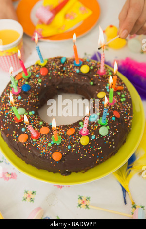 Femme allumant des bougies sur le gâteau d'anniversaire Banque D'Images