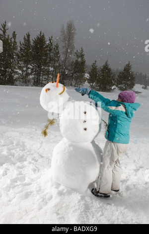 Fille poussant tête Bonhomme de neige, Comté de Summit, près de Frisco, Colorado, USA Banque D'Images