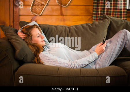 Woman Relaxing on Couch, Listening to MP3 Player Banque D'Images
