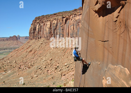 Un alpiniste rappeling le rock après avoir gravi une fissure dans l'UTAH Indian creek Banque D'Images