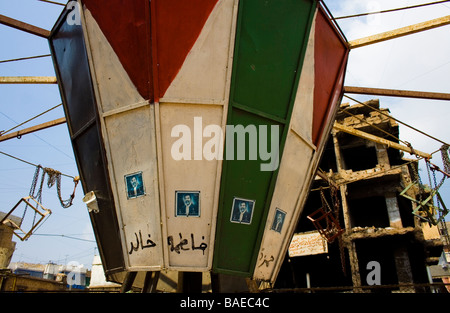 Un manège en face de la guerre déchirée des bâtiments avec des autocollants de propagande de Saddam Hussein dans un camp de réfugiés palestiniens Banque D'Images