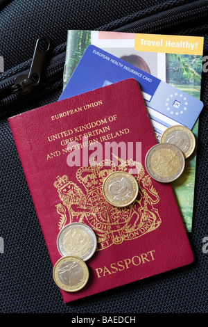 Close up d'un passeport britannique, CEAM carte santé et certaines devises étrangères assis sur le dessus d'une valise Banque D'Images