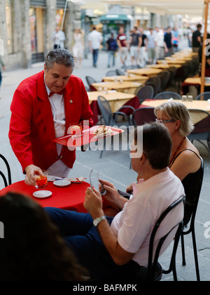 Un serveur sert un couple dans un café en plein air en Italie. Banque D'Images