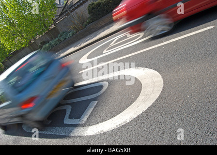 Le marquage routier britannique indiquant 20 milles à l'heure limite de vitesse, avec des voitures qui passent Banque D'Images