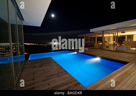 Un élégant et moderne de propriété résidentielle avec une piscine et donnant sur la mer, tourné de nuit avec une lune brillante. Banque D'Images