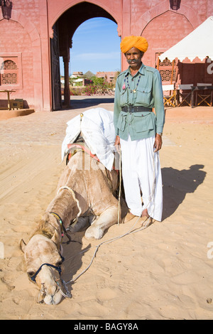 Homme debout à côté d'un chameau à Osian Camel Camp, Osian, Rajasthan, Inde Banque D'Images