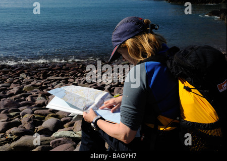 Femme walker reading a map et contrôler la route alors que le sentier côtier du Pembrokeshire Banque D'Images