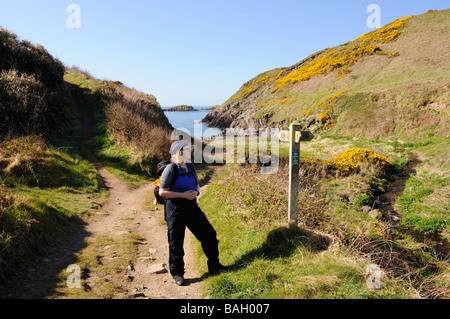 Walker à la femelle au panneau à Bwdy Bay sur la côte de Pembrokeshire Wales UK Banque D'Images