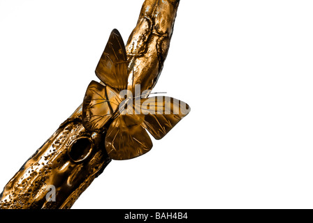 Papillon métal doré isolé sur blanc assis sur une branche. La sculpture. Banque D'Images