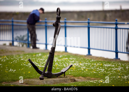 Adolescent solitaire s'appuie sur les garde-corps sur la rivière Mersey et contemple ses problèmes. Une ancre se trouve dans l'avant-plan Banque D'Images