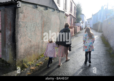 Après l'école une mère rentre chez elle avec ses filles après un orage à Cornwall Banque D'Images