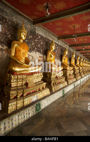 Statues de Bouddha en or la ligne galeries qui entourent le bâtiment principal de Wat Suthat à Bangkok en Thaïlande Banque D'Images