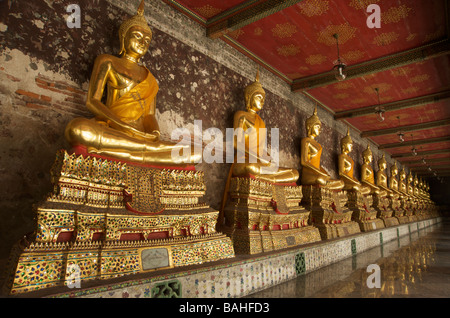 Statues de Bouddha en or la ligne galeries qui entourent le bâtiment principal de Wat Suthat à Bangkok en Thaïlande Banque D'Images