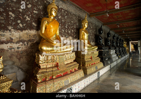 Une rangée de statues de Bouddha en or noir et la ligne des galeries à Wat Suthat temple à Bangkok en Thaïlande Banque D'Images