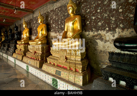 Une rangée de statues de Bouddha en or noir et la ligne des galeries à Wat Suthat temple à Bangkok en Thaïlande Banque D'Images