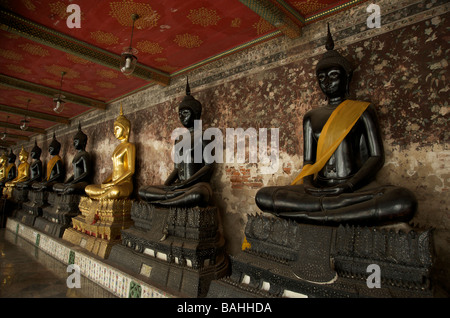 Une rangée de statues de Bouddha en or noir et la ligne des galeries à Wat Suthat temple à Bangkok Banque D'Images