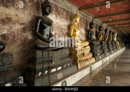 Une rangée de statues de Bouddha en or noir et la ligne des galeries à Wat Suthat temple à Bangkok Banque D'Images