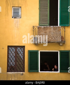 Un couple assis en train de déjeuner dans un shutterd fenêtre dans la Piazza Anfiteatro, Luca, Toscane, Italie Banque D'Images