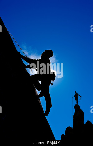 Un grimpeur se profile comme il fait son chemin jusqu'a steep rock face à la Sierra Nevada en Californie Banque D'Images