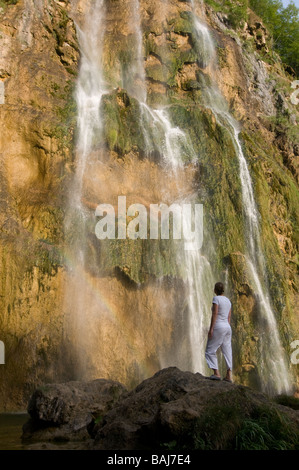 Jeune femme regarde la plus grande chute d'eau le long de la végétation du lac Plitvice Croatie rock l'Europe de l'Est Banque D'Images