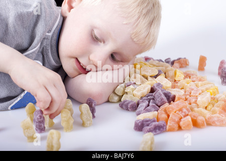 Jeune garçon plongé dans petit monde jouer avec jelly babies. Banque D'Images