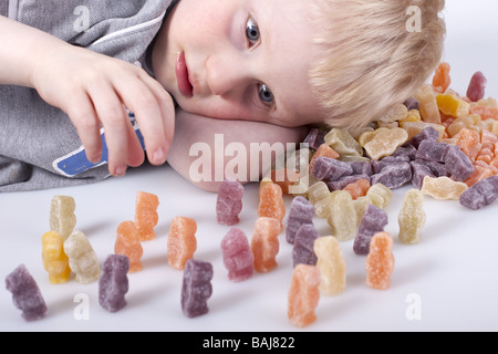 Jeune garçon plongé dans petit monde jouer avec jelly babies. Banque D'Images