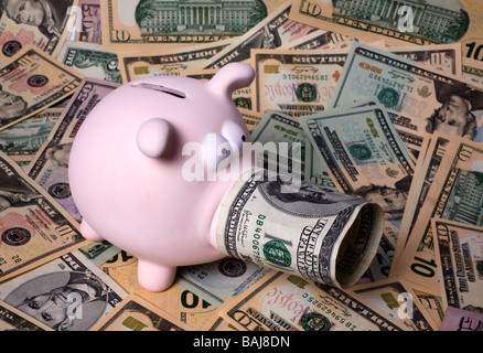 Pink piggy bank sur un tapis de billets de dollars américains de diverses confessions et avec 100 dollars à côté Banque D'Images