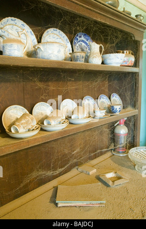 Welsh dresser avec de la porcelaine et des plaques de métal, pichets, tasses, couverts d'une épaisse couche de poussière. Chambre pas nettoyée pendant 20 ans Banque D'Images