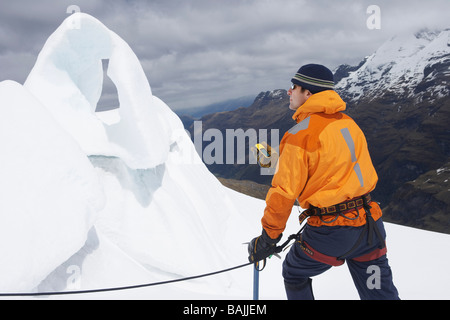 D'alpiniste holding compas sur la formation de glace dans les montagnes enneigées Banque D'Images