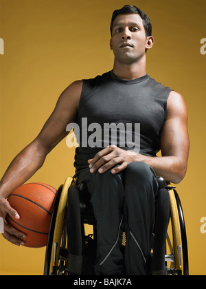 Athlète paraplégique sitting in wheelchair holding basketball Banque D'Images