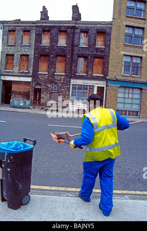 Street Cleaner dans une rue à bord de maisons victoriennes délabrées Londres SE1 Angleterre Banque D'Images