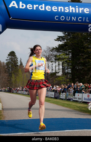 Femme d'exécution en kilt en tartan. Les concurrents sur la ligne d'arrivée à l'Aberdeenshire Council Exécutez 'le château de Balmoral road races' Samedi 25 Avril 2009 Banque D'Images