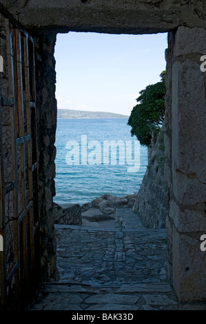 Vue sur la mer par un passage entre les maisons de la vieille ville de Baska, île de Krk, Croatie Banque D'Images