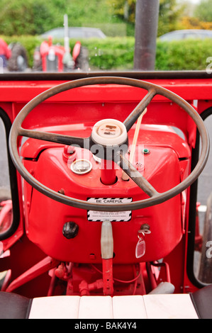 L'intérieur de la cabine d'un tracteur de ferme vintage rouge montrant volant, clé de contact et compose. Banque D'Images