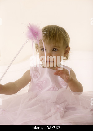 Porter un enfant en robe rose tenant une baguette magique Banque D'Images