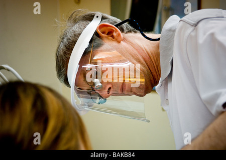 Homme dentiste avec un bouclier de protection en plastique à l'œuvre dans une clinique moderne Banque D'Images