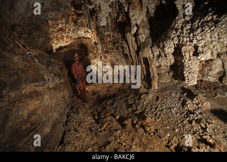Une fédération de spéléologues stands et admire le beau cave formations qui jonchent les murs dans cette grotte souterraine profonde Chine Banque D'Images