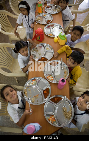 Les enfants de manger un repas à l'école à Hazira, près de Surat. Le Gujarat. L'Inde Banque D'Images