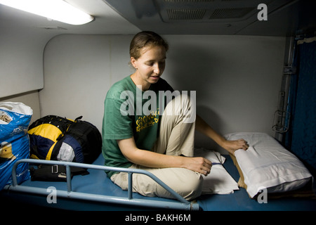 Passager de l'Europe de l'Ouest fait son lit dans un compartiment couchette de deuxième classe d'un train indien. Banque D'Images