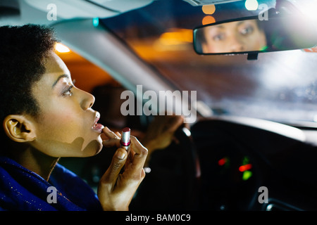 Woman putting on lipstick in car Banque D'Images