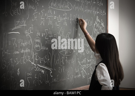 Girl writing on blackboard Banque D'Images